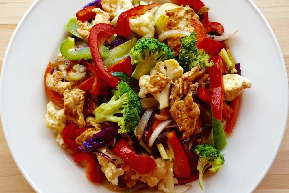 A colourful stir fry with chicken, peppers, broccoli, and fresh vegetables